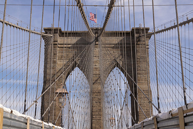 Manhattan-side tower of the Brooklyn Bridge in New York City (USA) with the national flag flying half-staff on top. Photo courtesy of NormanB.